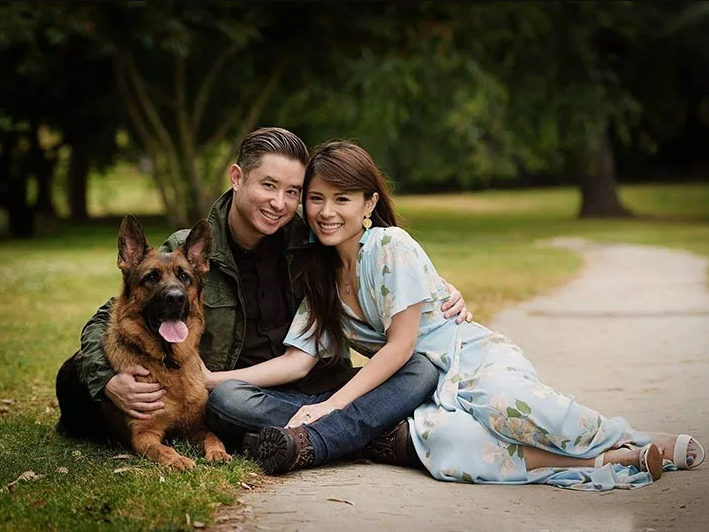 Couple sitting on grass with their German Shepherd