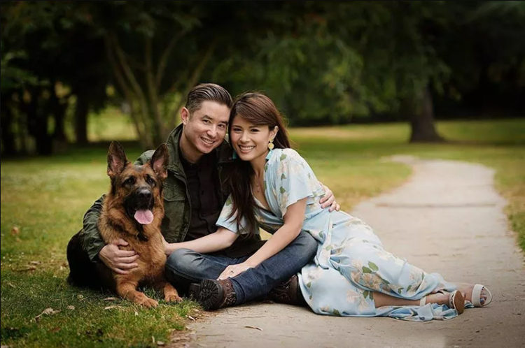 Couple sitting on grass with their German Shepherd