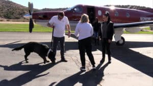 Michael and Jeannette Kempkes on a private airport runway with black German Shepherd dog and guests.